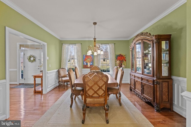 dining area with an inviting chandelier, ornamental molding, and light wood-type flooring