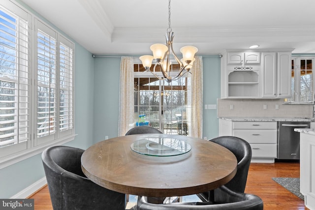 dining room featuring crown molding, a tray ceiling, a chandelier, and light hardwood / wood-style flooring