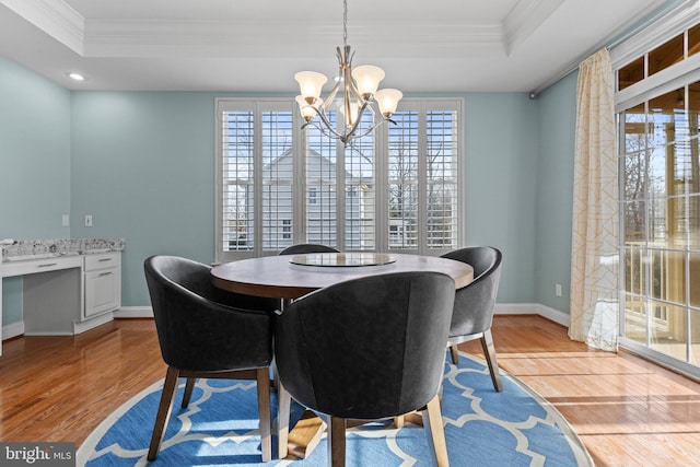 dining area featuring a healthy amount of sunlight, a tray ceiling, and light hardwood / wood-style flooring