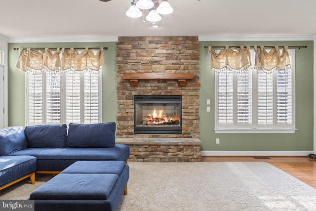 living room with crown molding, a stone fireplace, and wood-type flooring