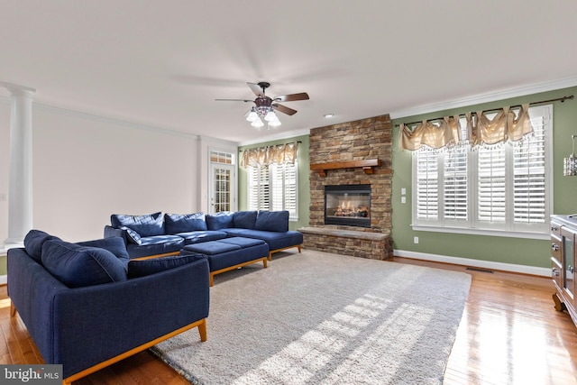 living room featuring crown molding, a healthy amount of sunlight, a fireplace, and wood-type flooring