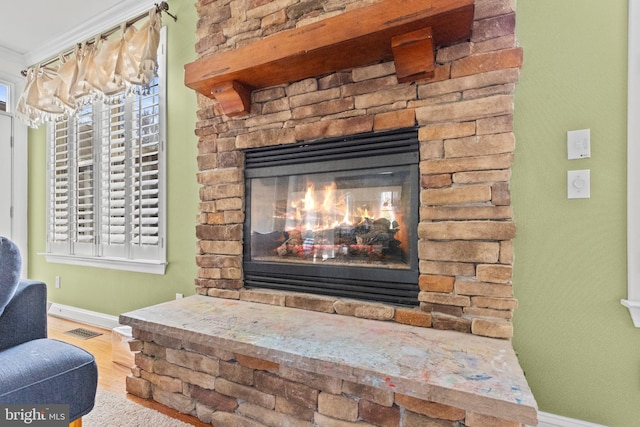 details featuring a stone fireplace, wood-type flooring, and ornamental molding