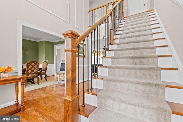 stairs with hardwood / wood-style flooring, crown molding, and a towering ceiling