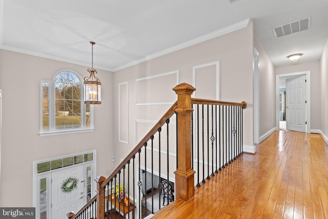 hallway with hardwood / wood-style floors, a notable chandelier, and ornamental molding