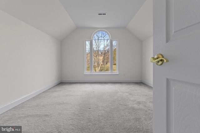 bonus room with vaulted ceiling and light colored carpet