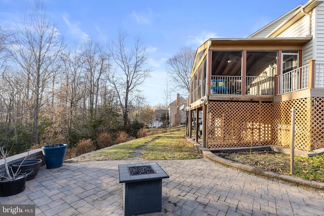 view of patio / terrace featuring a sunroom and a fire pit