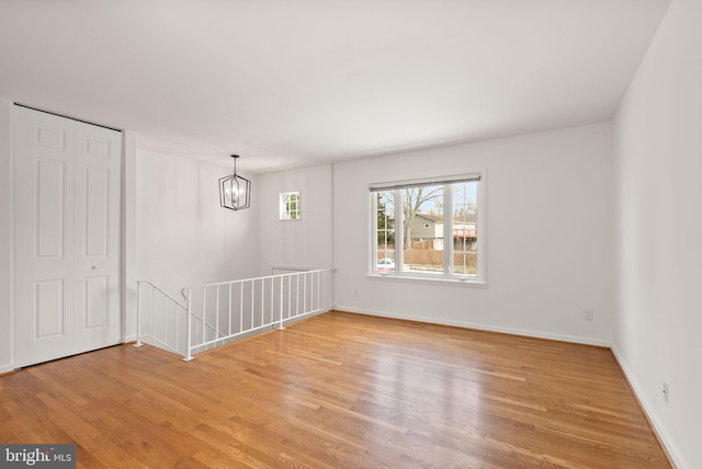 spare room with a chandelier and light wood-type flooring