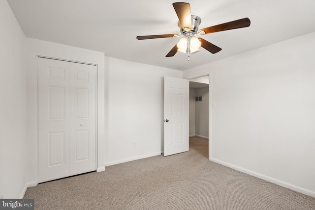 unfurnished bedroom with light carpet, a closet, and ceiling fan