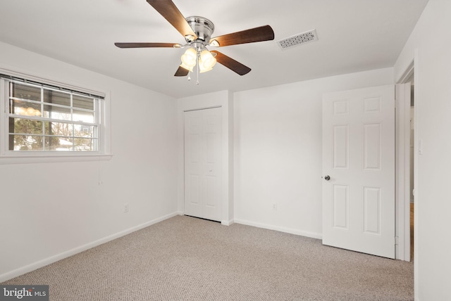 unfurnished bedroom with ceiling fan, a closet, and light carpet