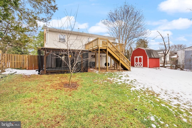 back of house with central AC unit, a storage shed, a deck, and a lawn