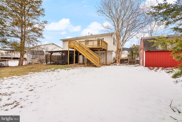 snow covered back of property with a deck and a shed