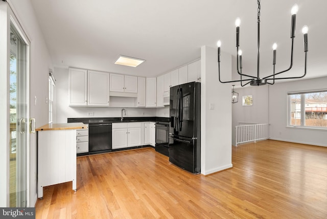 kitchen with butcher block counters, white cabinetry, a chandelier, light hardwood / wood-style floors, and black appliances