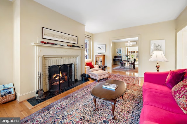 living room with a fireplace, a notable chandelier, and wood-type flooring