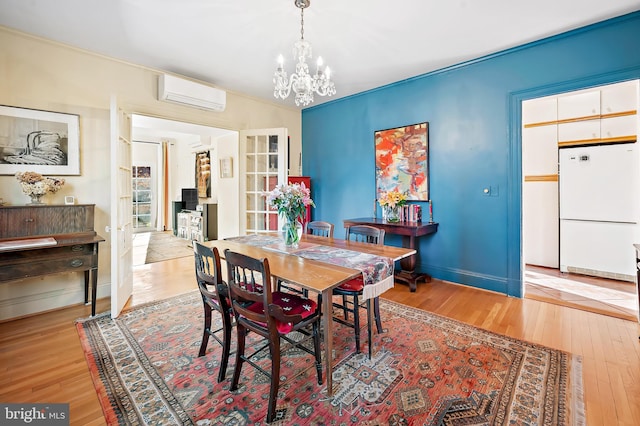 dining area featuring a notable chandelier, light wood-type flooring, and an AC wall unit