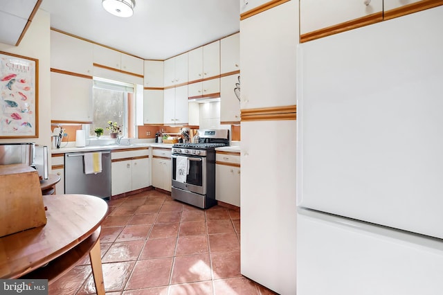 kitchen with appliances with stainless steel finishes, white cabinets, and light tile patterned floors