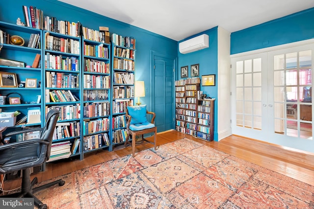 sitting room with hardwood / wood-style floors, french doors, and a wall unit AC