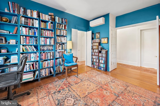 living area featuring hardwood / wood-style floors and a wall mounted air conditioner