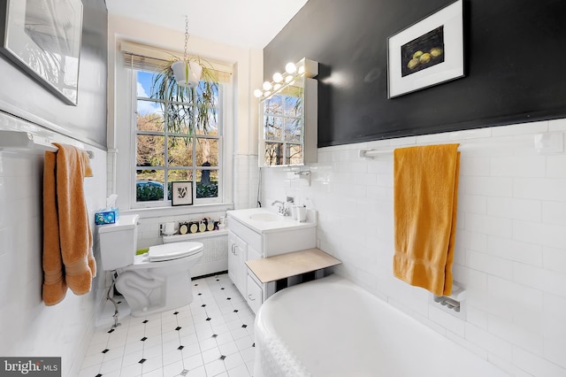 bathroom with tile walls, vanity, a washtub, tile patterned flooring, and toilet