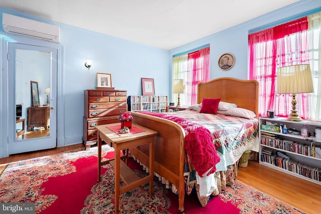 bedroom featuring hardwood / wood-style floors and a wall mounted AC