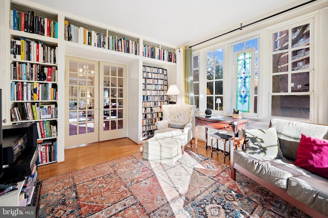 living area featuring hardwood / wood-style floors, french doors, and an inviting chandelier