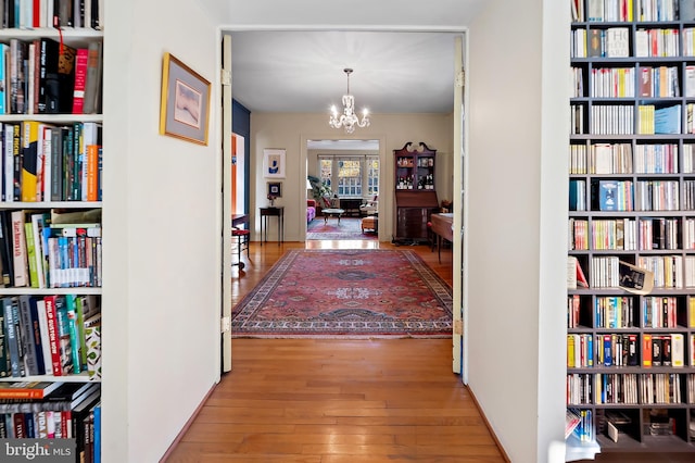 corridor with a notable chandelier and hardwood / wood-style floors