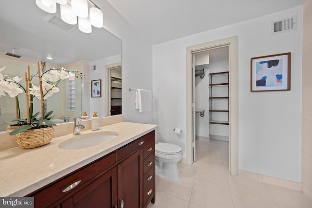 bathroom with visible vents, toilet, tiled shower, tile patterned floors, and vanity