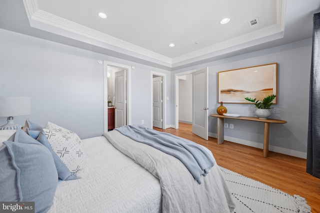 bedroom with crown molding, baseboards, a tray ceiling, recessed lighting, and wood finished floors