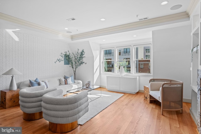 living room featuring visible vents, radiator heating unit, an accent wall, and wood finished floors