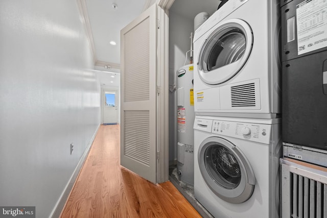 clothes washing area with baseboards, laundry area, light wood-style flooring, stacked washer and dryer, and electric water heater