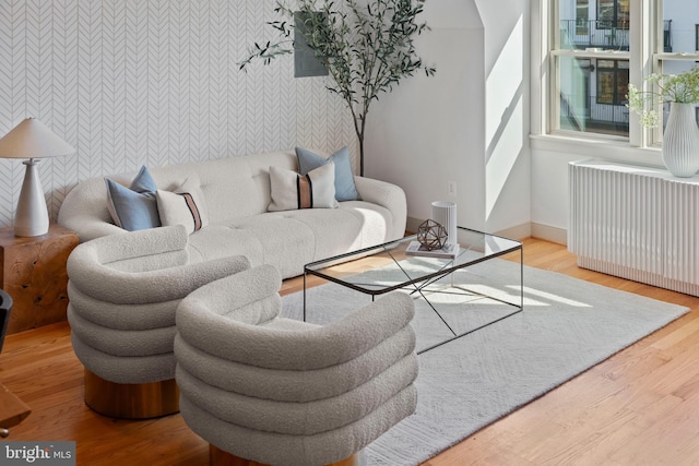 living room with wood finished floors, radiator heating unit, baseboards, and an accent wall