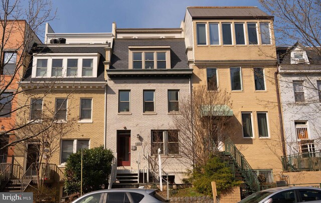 townhome / multi-family property featuring mansard roof and brick siding