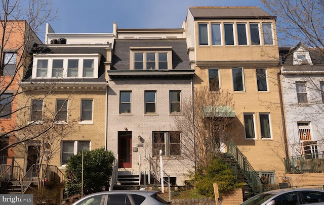 townhome / multi-family property featuring mansard roof and brick siding