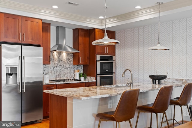 kitchen featuring visible vents, decorative light fixtures, backsplash, appliances with stainless steel finishes, and wall chimney range hood