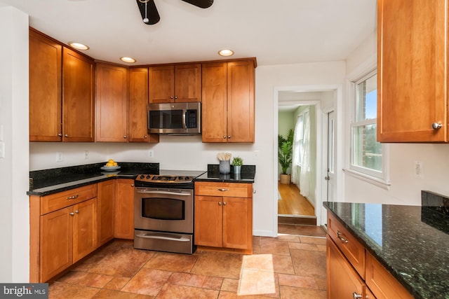 kitchen with baseboards, dark stone counters, recessed lighting, brown cabinets, and stainless steel appliances