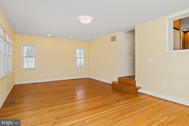 spare room featuring light wood-style floors, visible vents, and baseboards