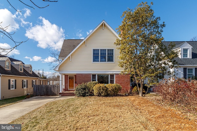 view of front of property with brick siding, a front lawn, and fence