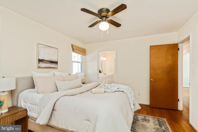 bedroom with a ceiling fan, wood finished floors, baseboards, and connected bathroom