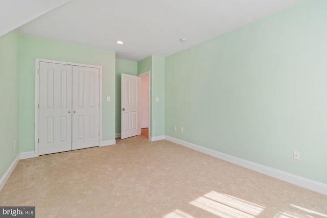 unfurnished bedroom with light carpet, recessed lighting, a closet, and baseboards