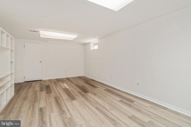 below grade area with baseboards, visible vents, and light wood finished floors