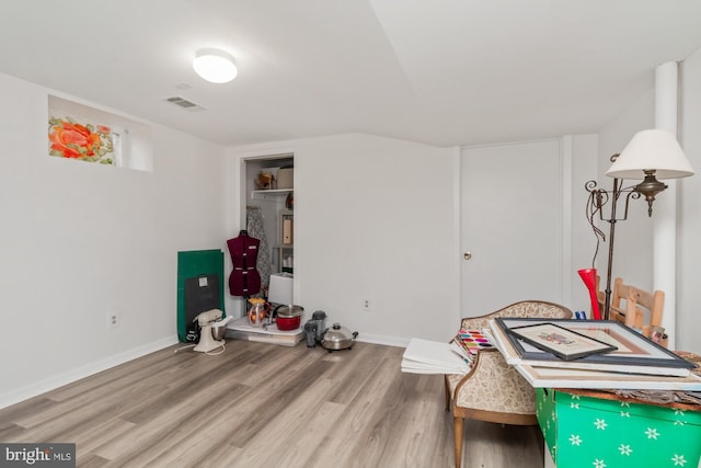 interior space featuring visible vents, baseboards, wood finished floors, and vaulted ceiling