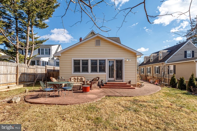 rear view of house featuring entry steps, a patio area, fence, and a lawn