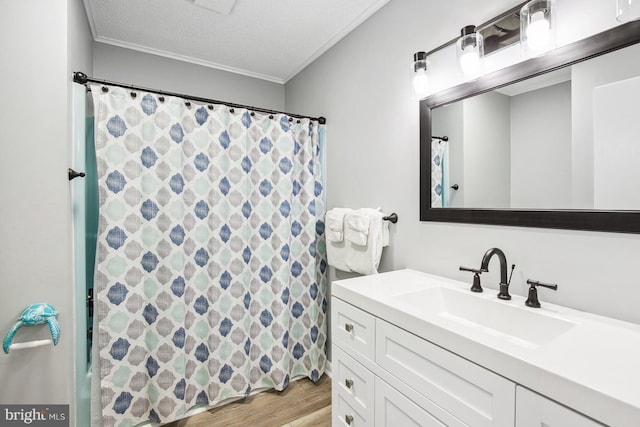 bathroom featuring vanity, hardwood / wood-style floors, crown molding, and a textured ceiling