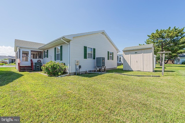 back of property featuring a storage unit, central AC unit, a lawn, and a sunroom