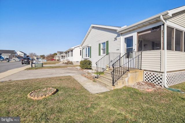 view of home's exterior with a lawn and a sunroom