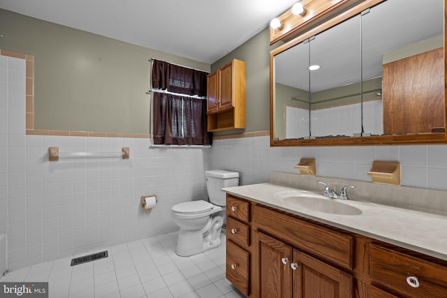 bathroom featuring toilet, tile patterned flooring, vanity, and tile walls