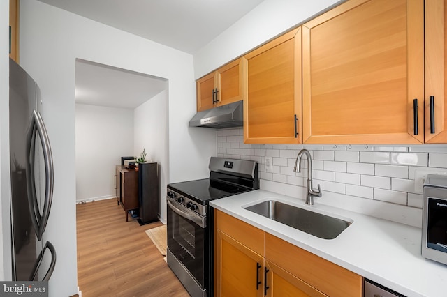 kitchen featuring appliances with stainless steel finishes, sink, backsplash, and light hardwood / wood-style floors