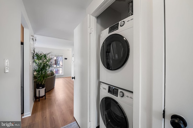 laundry room featuring hardwood / wood-style flooring and stacked washer and clothes dryer