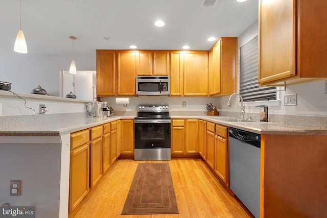 kitchen with decorative light fixtures, sink, light hardwood / wood-style floors, kitchen peninsula, and stainless steel appliances