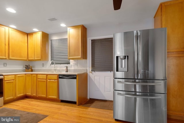 kitchen with ceiling fan, appliances with stainless steel finishes, sink, and light hardwood / wood-style flooring