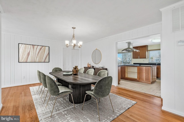 dining room with crown molding, a chandelier, and light hardwood / wood-style flooring